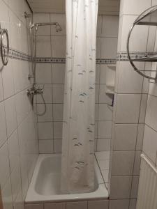 a bathroom with a shower with a white shower curtain at Apartment Ostsee Haus Sandra in Dahme