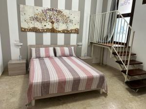 ein Schlafzimmer mit einem Bett mit einer gestreiften Decke und einer Treppe in der Unterkunft APP. TURISTICO ARCO NORMANNO in Mazara del Vallo