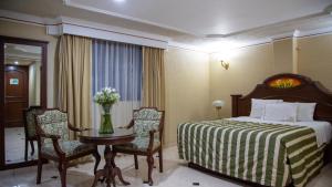 グアダラハラにあるホテル カジノ プラザのベッド、テーブル、椅子が備わるホテルルームです。