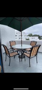 een tafel en stoelen met een parasol op een patio bij Hermoso departamento a pasos de la playa! in Tonsupa