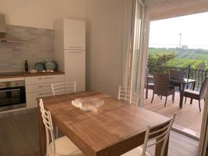 uma cozinha com uma mesa de madeira com cadeiras e uma varanda em Appartamentino3 Collina Costa Dei Trabocchi em Villalfonsina