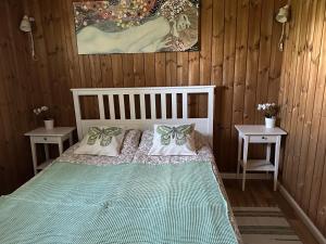 1 dormitorio con 1 cama con 2 mesas y 1 pintura en Villa Vita, en Seimėnai