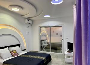 una camera con tende viola, un letto e una TV di Master Suite in Bellavista Andalucia with Pool and Beach a Al Matlīn
