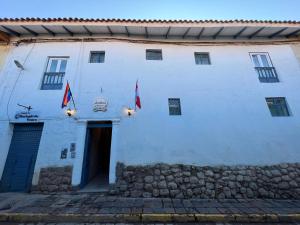 un bâtiment blanc avec deux drapeaux devant lui dans l'établissement Hotel Andina, à Cusco