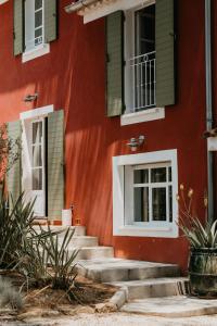 a red building with green windows and stairs at Le Cigalon in Le Beausset