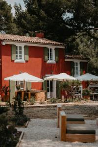 a red house with tables and umbrellas in front of it at Le Cigalon in Le Beausset
