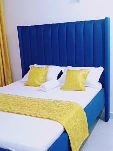 a bed with a blue headboard and two yellow pillows at Medzam Homes Spacious Newly Furnished Studio in Mombasa