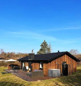 a large wooden cabin with a deck in a field at Cosy place with adoring sunny terrace in Vejby