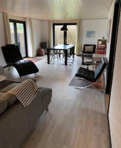 een woonkamer met een bank, stoelen en een tafel bij Cosy place with adoring sunny terrace in Vejby
