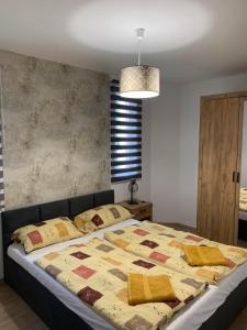 a bedroom with a bed with a quilt on it at Marcipán Apartman in Balatonlelle