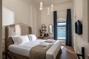 a bedroom with a bed with a television and a window at Palazzo di Sitia Luxury Suites in Sitia