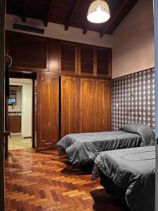 a bedroom with two beds and a wooden floor at Valentino House piscina internet parking desayuno in Mendoza