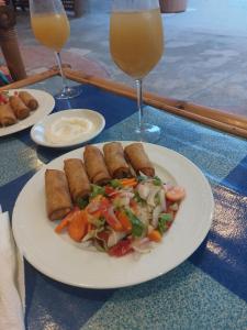 un plato de comida en una mesa con dos vasos de zumo de naranja en Blue Palm Resort Ghana, en Abia