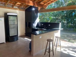 eine Küche mit einer Theke und Hockern in einem Zimmer in der Unterkunft Casa Paraíso - Cond Costa do Sol- Bertioga in Bertioga
