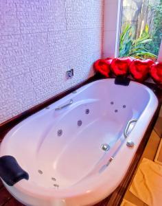 a bath tub with red roses on top of it at Prana Guest House in Praia do Rosa