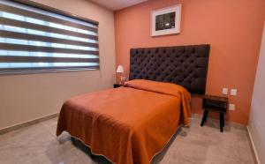 a bedroom with a bed with an orange blanket and a window at Palacio Huatulco - 2I in Santa Maria Huatulco +5 photos