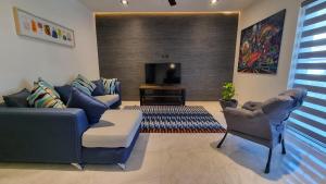 a living room with a couch and chairs and a television at Palacio Huatulco - 2I in Santa Maria Huatulco
