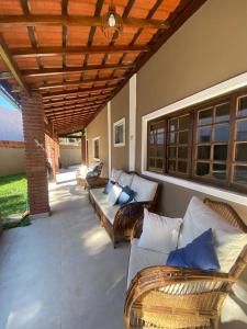 a patio with wicker couches and chairs under a roof at Casa Paraíso - Cond Costa do Sol- Bertioga in Bertioga