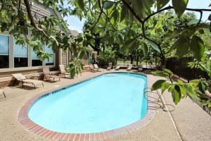 a swimming pool with chairs and a tree at Overland Park Condo, Close to Lakes and Parks! in Overland Park