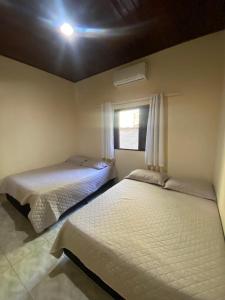 ein Schlafzimmer mit zwei Betten und einem Fenster in der Unterkunft Casa Paraíso - Cond Costa do Sol- Bertioga in Bertioga + 32 Fotos