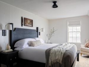 een slaapkamer met een groot wit bed en een stoel bij Bluebird Ocean Point Inn in Ocean Point