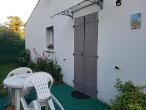 a patio with two chairs and a table and a door at La salamandre, Chambre d'hôtes in Étaules +15 photos