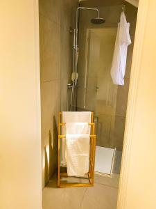 La salle de bains est pourvue d'une douche et d'une serviette accrochée au mur. dans l'établissement Lisbon-Room Com, à Algés