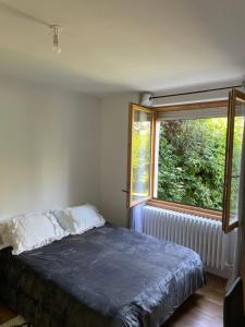 een slaapkamer met een bed voor een raam bij Chambre privée vue sur le jardin proche centre ville in Besançon