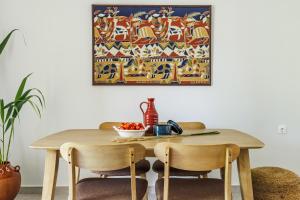 une table à manger avec des chaises et un tableau mural dans l'établissement Yianna Sunny Studios, à Skopelos