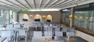 un restaurante con mesas y sillas blancas y una pared de ladrillo en Hotel Am Limes, en Enns
