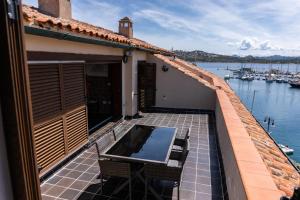 a balcony with a table and chairs next to the water at Penthouse Cala Gavetta in La Maddalena