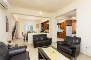 a living room with leather furniture and a kitchen at Villa Kleopatra in Paphos