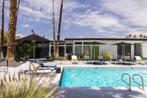 a pool with chairs and umbrellas next to a house at The Three Fifty Hotel, A Kirkwood Collection Hotel in Palm Springs