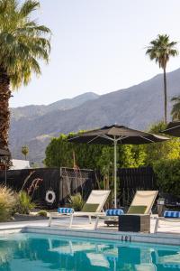 a swimming pool with two chairs and an umbrella at The Three Fifty Hotel, A Kirkwood Collection Hotel in Palm Springs