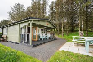 una piccola cabina verde con tavolo e tavolo da picnic di Torr Lodge- luxury log cabin with private hot tub! a Ballycastle