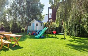 um parque infantil com escorrega e uma casa num quintal em 1 Bedroom Pet Friendly Home In Dabki em Dąbki