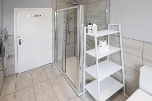 a bathroom with a shower and a white shelving unit at Spacious&Comfy 2 bed in Camden Town&Kings cross in London