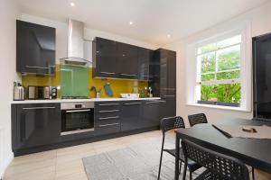 a kitchen with black cabinets and a table with chairs at Spacious&Comfy 2 bed in Camden Town&Kings cross in London