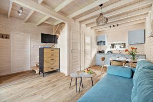 a living room with a blue couch and a kitchen at Natura Jantar - Całoroczne domy drewniane in Jantar