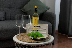 una botella de vino y un plato de uvas y copas de vino en Apartamento Veronika en Arrecife