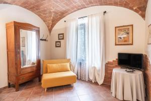 a living room with a chair and a tv at APPARTAMENTI LE GINESTRE 10 in Murlo