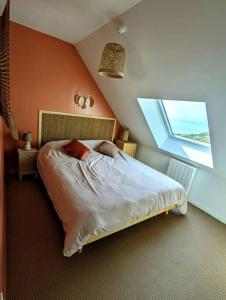 een slaapkamer met een bed en een groot raam bij Duplex au calme avec vue sur les dunes et la mer in Ambleteuse