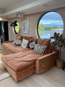 a large couch in a living room with a large window at Classy House Boat on Penton Hook Marina - walking distance Thorpe Park in Thorpe