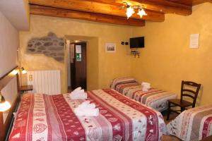 a hotel room with four beds and a tv at La Slitta in Roure Turin