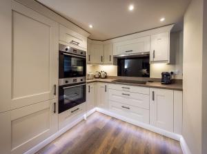 a white kitchen with white cabinets and wooden floors at The Farmhouse, Sebergham, near Caldbeck in Sebergham