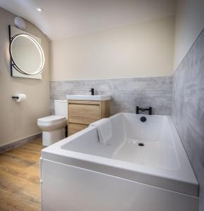 a white bath tub in a bathroom with a toilet at The Farmhouse, Sebergham, near Caldbeck in Sebergham