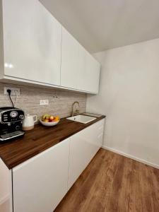 a kitchen with white cabinets and a bowl of fruit on the counter at CASTLE HILL apt in Old Town of Bratislava with free parking in Bratislava