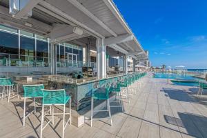 Daytona Grande Oceanfront Resort في دايتونا بيتش: بار فيه كراسي خضراء ومسبح