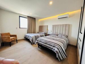 una habitación de hotel con dos camas y una silla en Elegante depa vista al malecón y mar by G P S rentas, en Mazatlán 37 fotos más