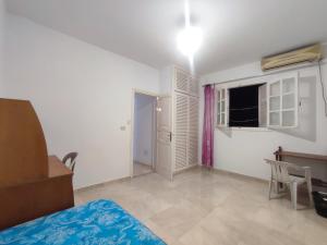 a bedroom with a bed and a table and a window at Calm place and near to the beach in Monastir